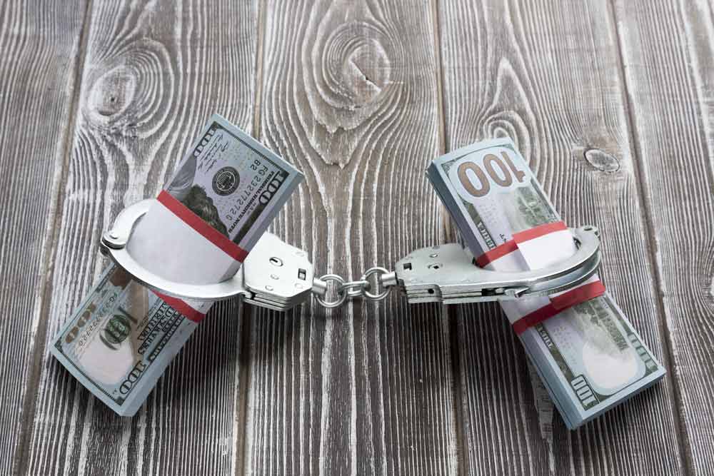 Two stacks of hundred dollar bills held together with handcuffs