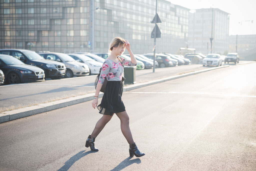 A young woman jaywalks across a California road